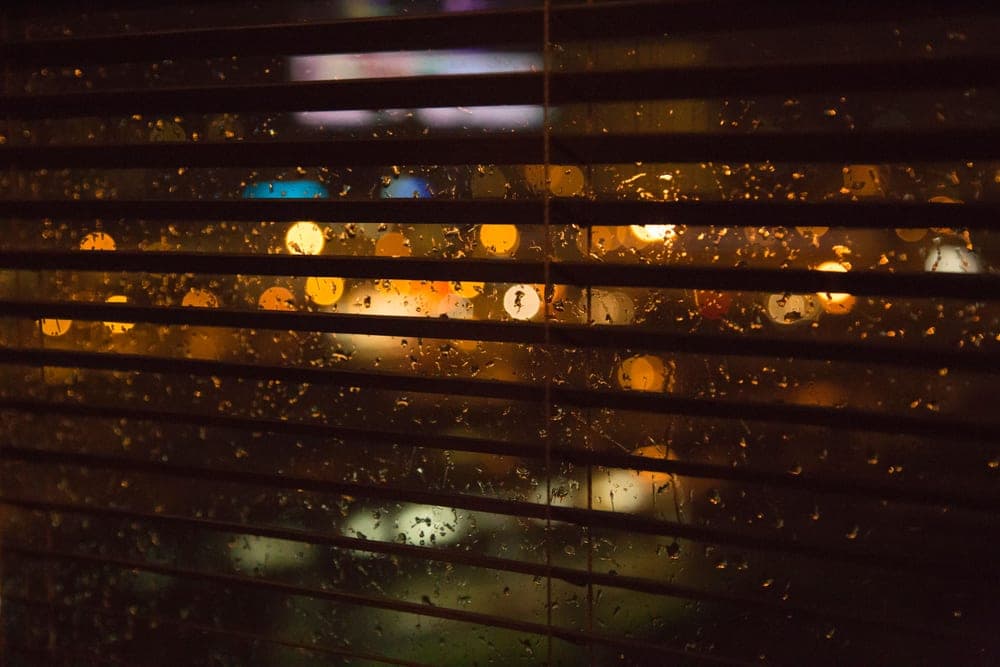 Streetlight shining through the slats of a bedroom blind at night