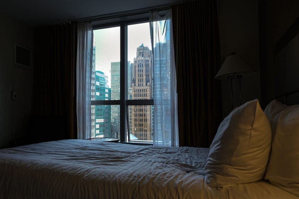 Open bedroom window at night with a curtain moving in the breeze