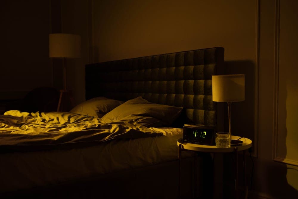 Bedside clock reading the early hours in a dark room