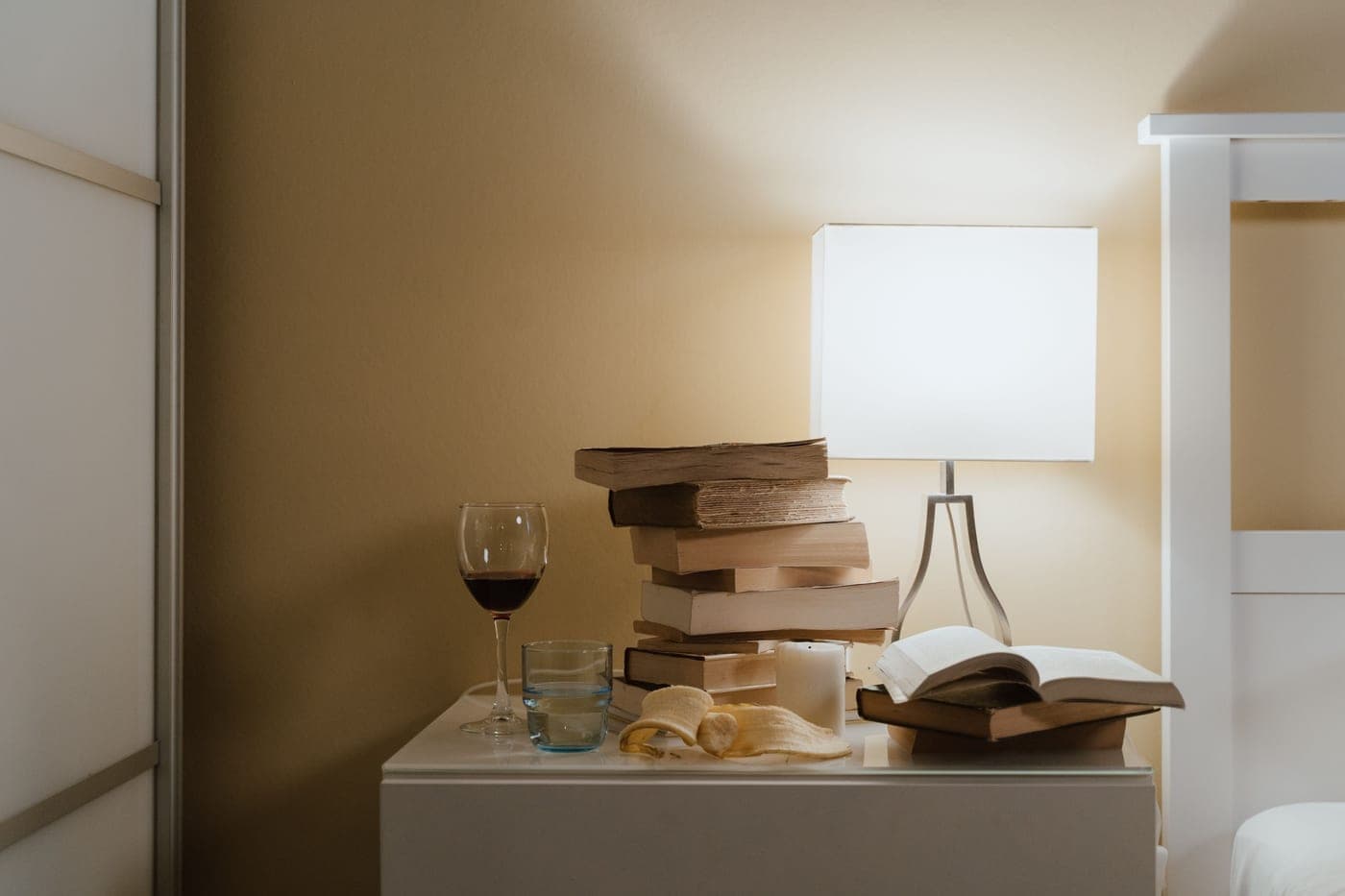 Tidy bedside table with a lamp, a book and a glass of water at night