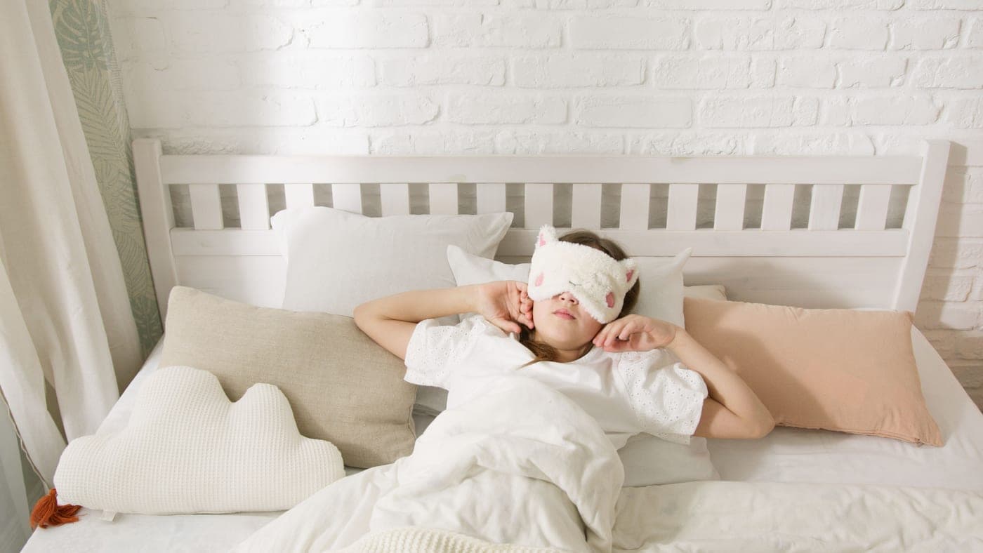 Person asleep in bed wearing a sleep mask - illustrative category image