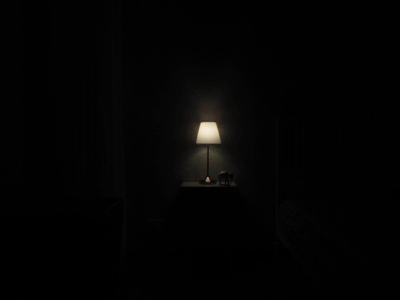 Small lit device on a bedside table in a dark room - illustrative category image