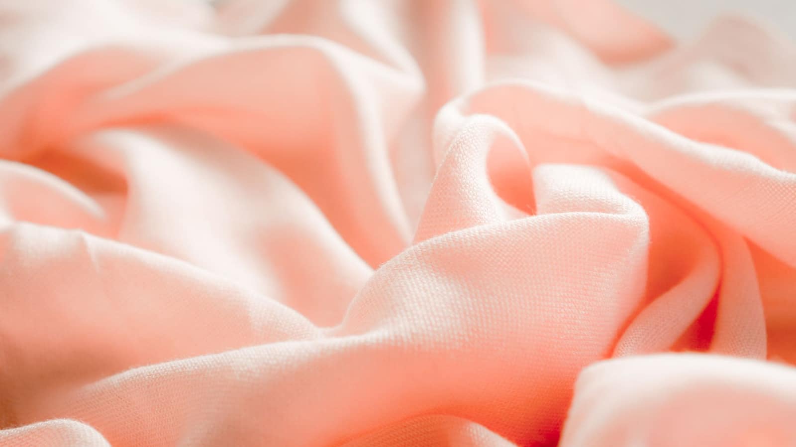 Close-up of soft silk fabric folded on pale bedding