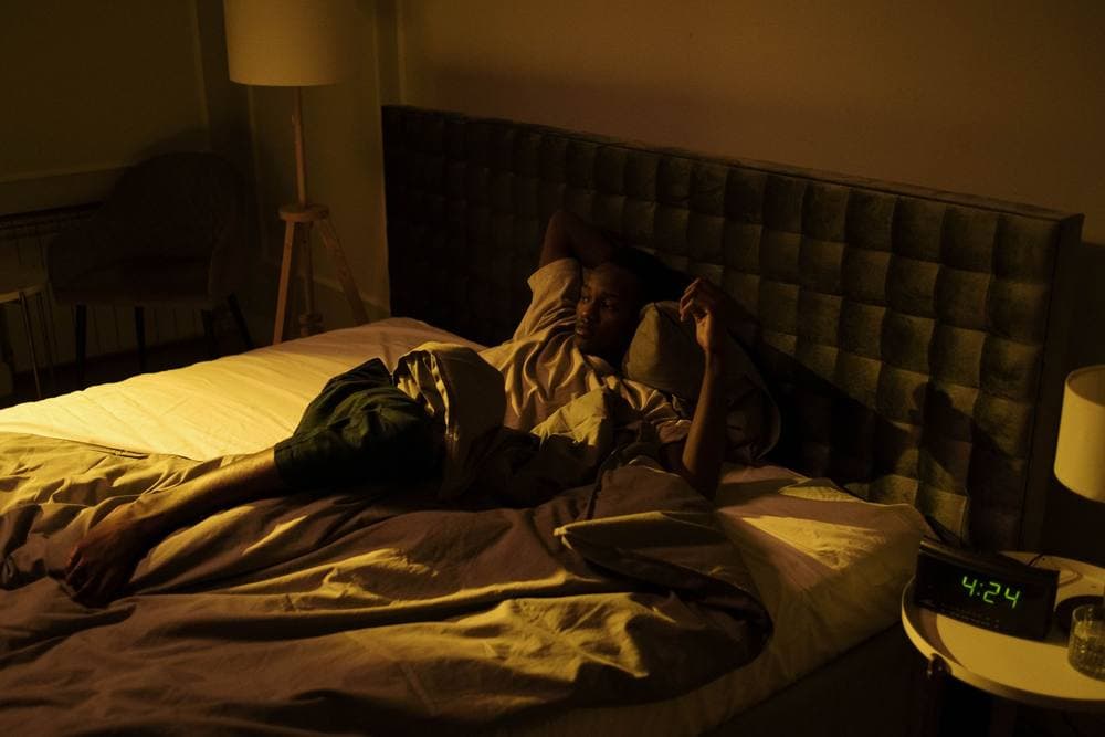 Person lying awake in a dimly lit bedroom late at night