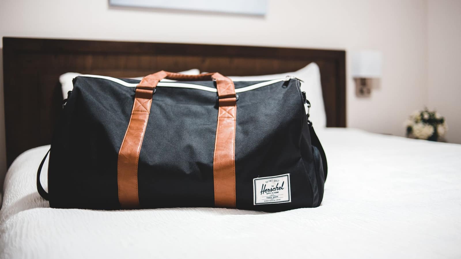 Open carry-on case being packed on a hotel bed
