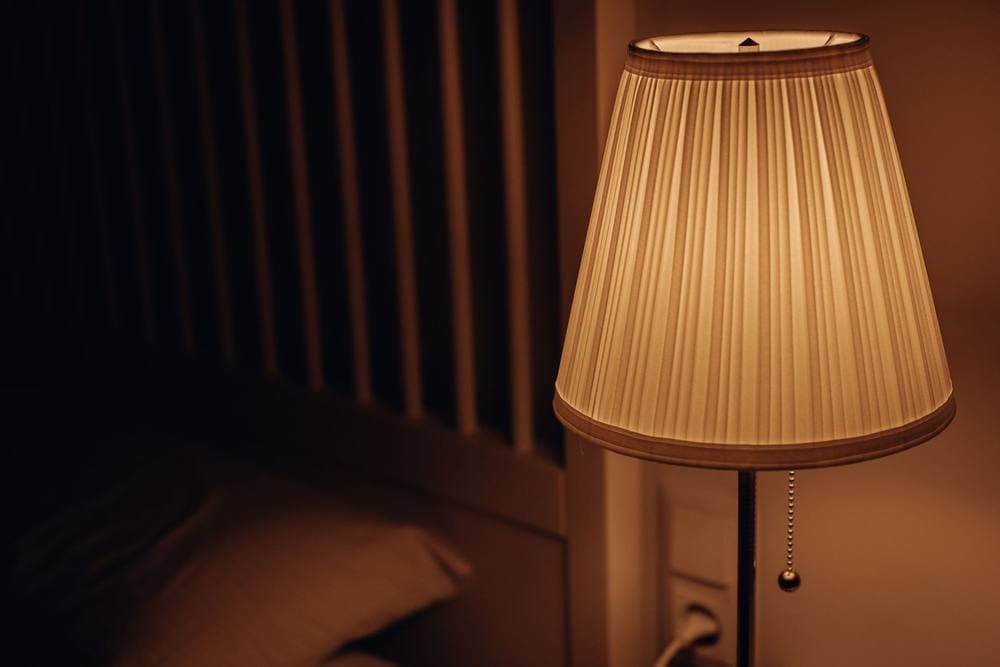 Dimly lit bedside lamp casting a warm glow in a bedroom - illustrative category image