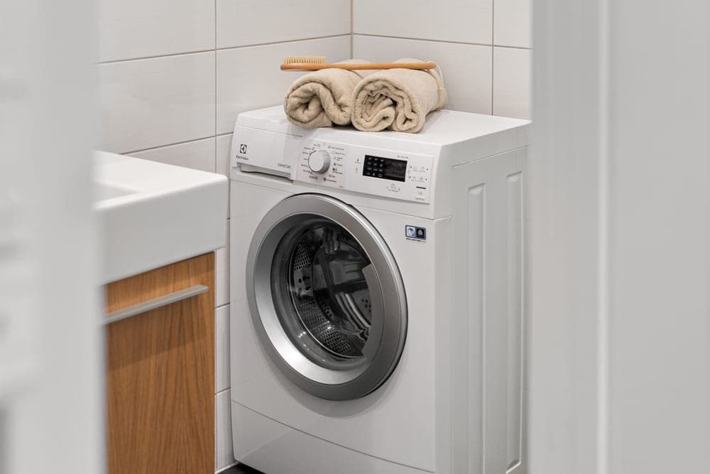 Folded clean linens beside a washing machine