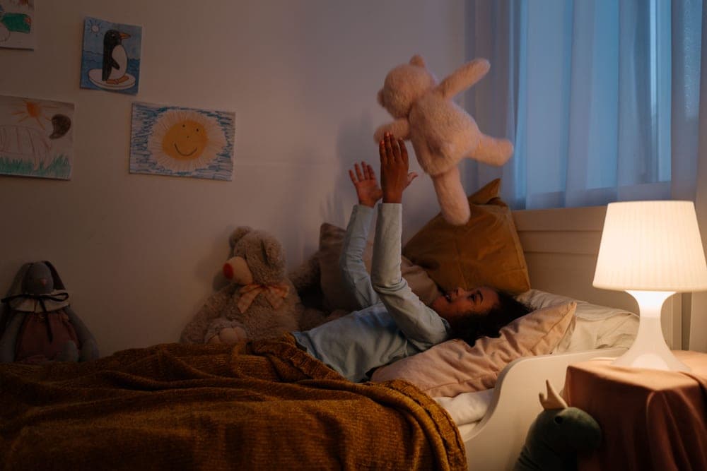 Tidy child's bedroom with a made bed and a soft toy in evening light