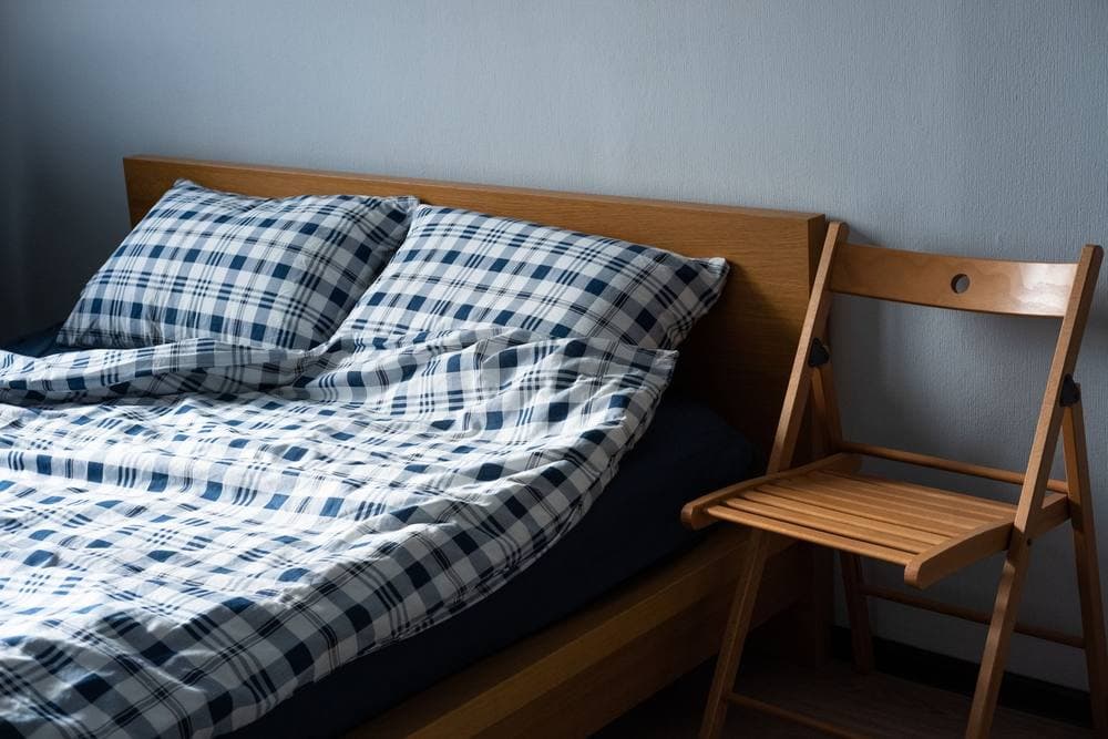 Bedroom with plaid bed linen and wooden furniture