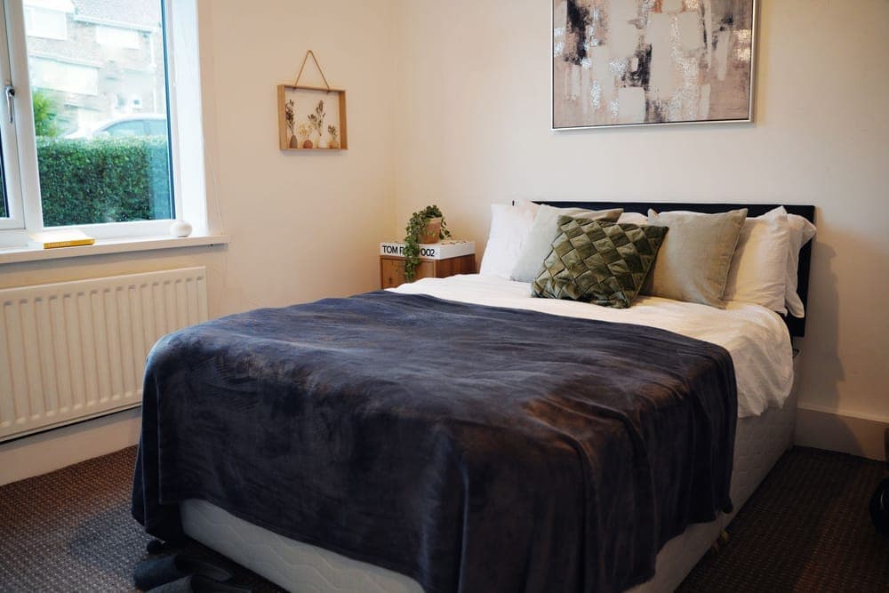 Neatly made double bed with a blanket folded across it