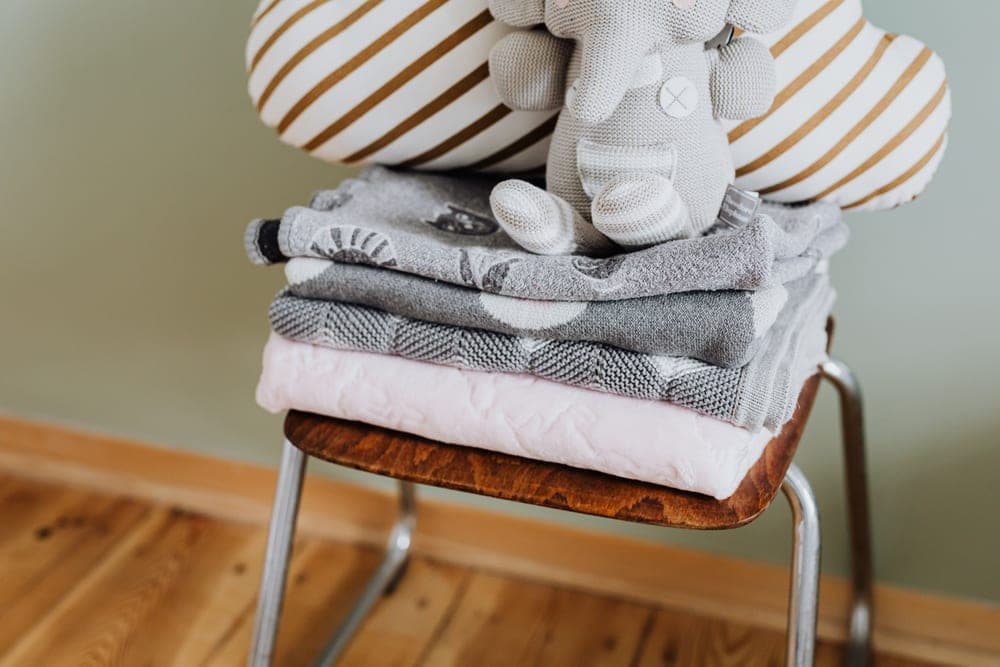 Folded blankets stacked neatly on a wooden bench