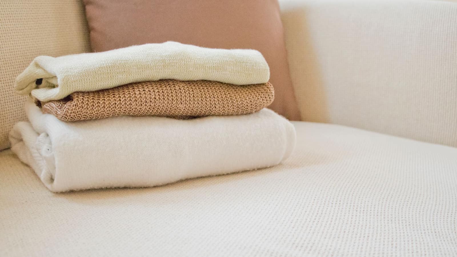 Heavy folded blanket resting on a neatly made bed in neutral tones
